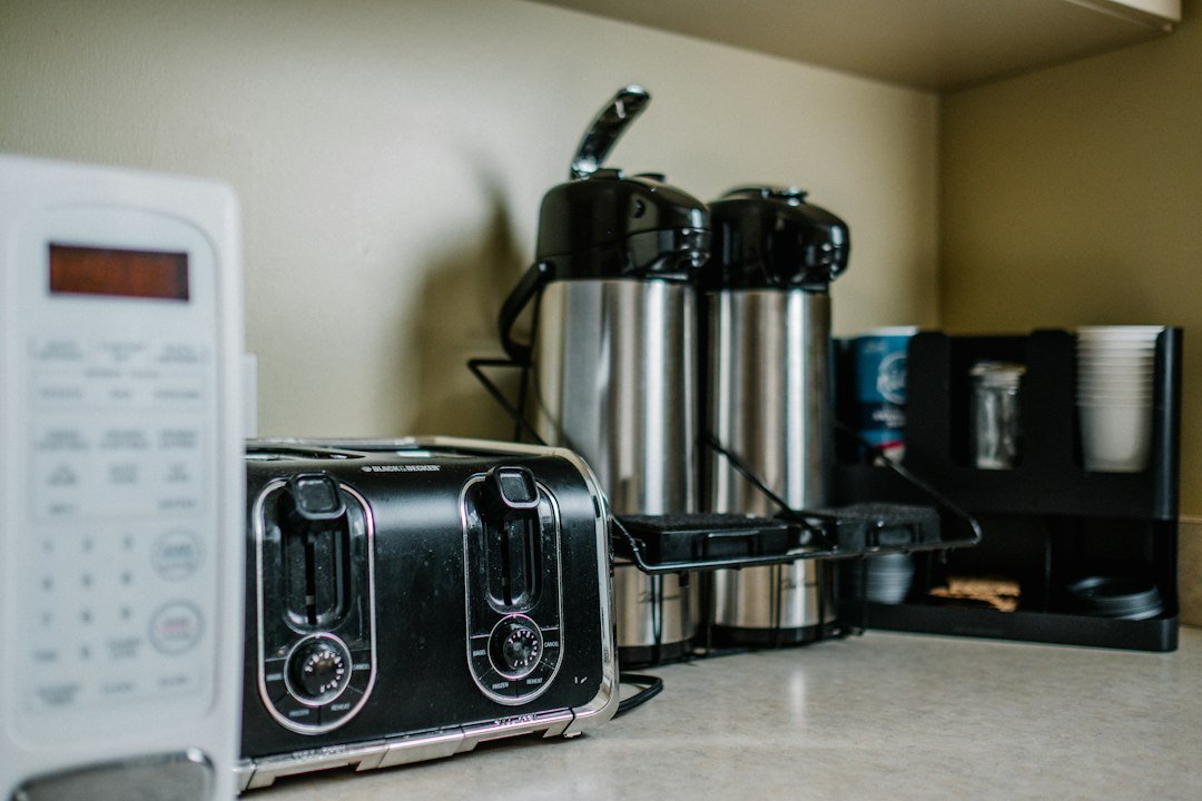 Stainless steel slot toaster on a wooden surface.