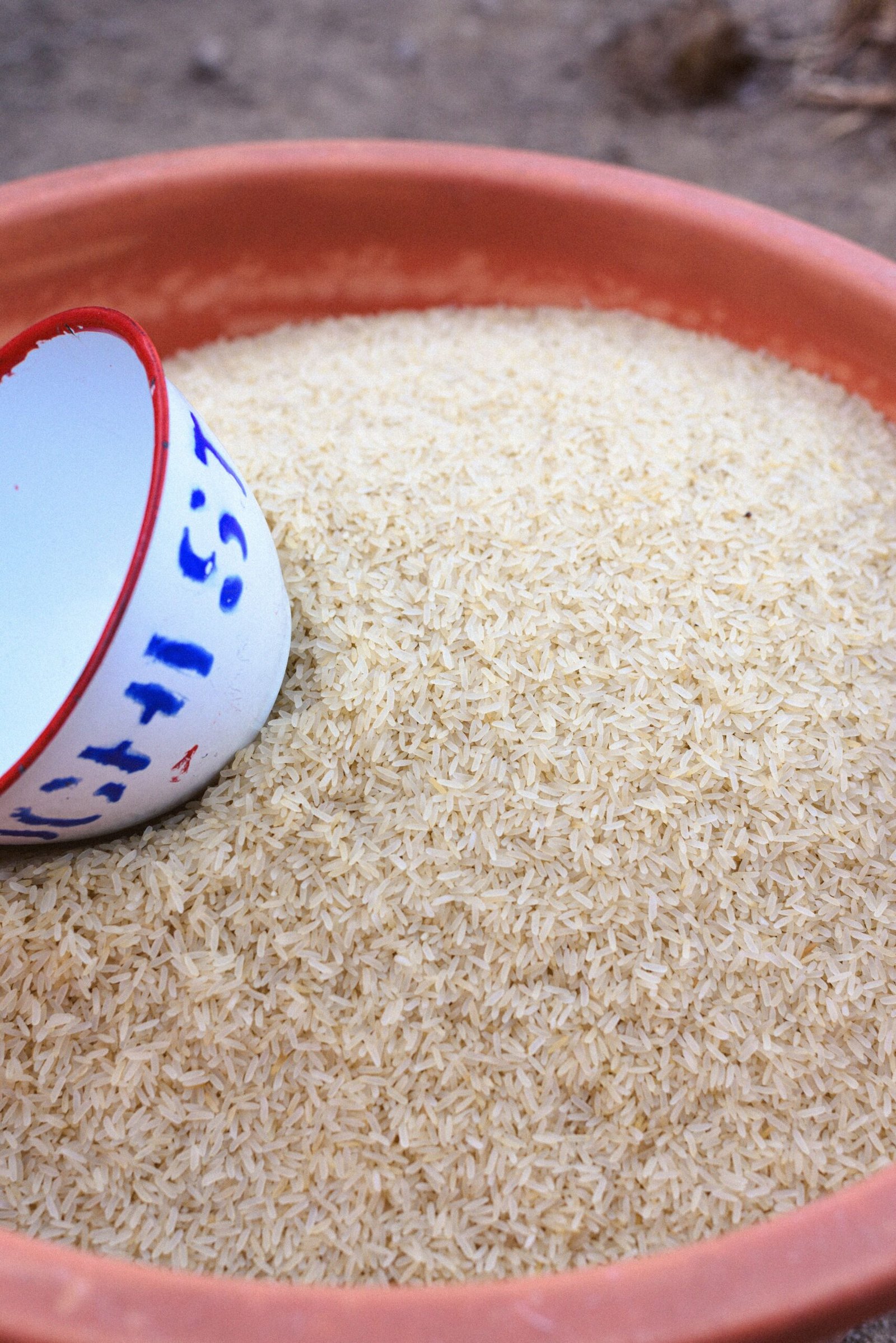 Uncooked rice beside a measuring cup.