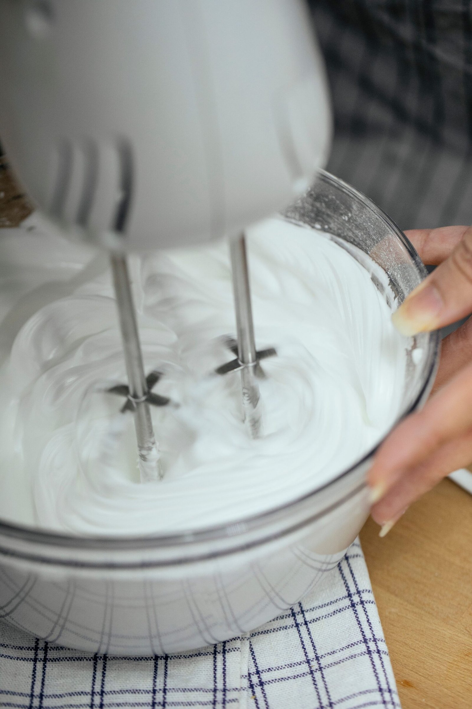 Hand mixer whipping ingredients in a bowl.